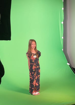 Young female student standing in front of a green screen