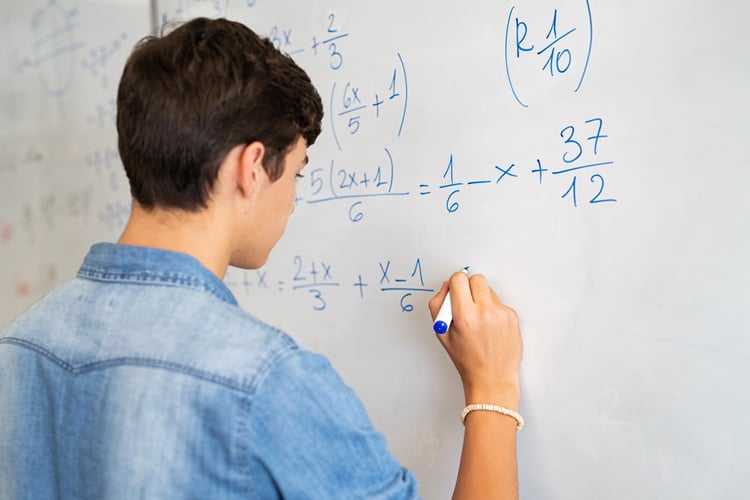 teenage male doing math on a whiteboard