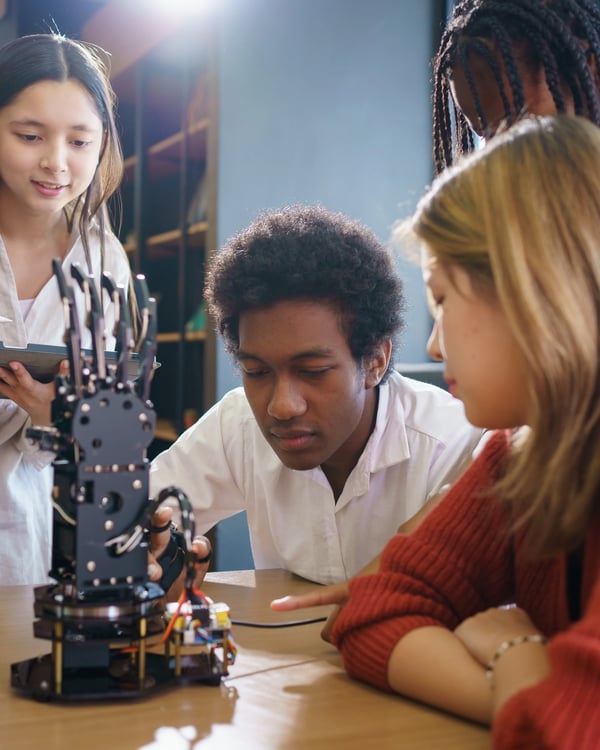 group of students looking at robotic arm