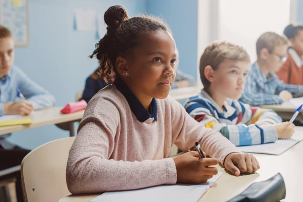 young african american girl listening to a teacher with other students nearby