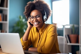 african american woman on a phone call while smiling at a laptop